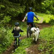 far trekker datter på sykkel i skogen med kidreel