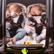 Two babies sleeping peacefully in Nordic Cab bike trailer with net cover.